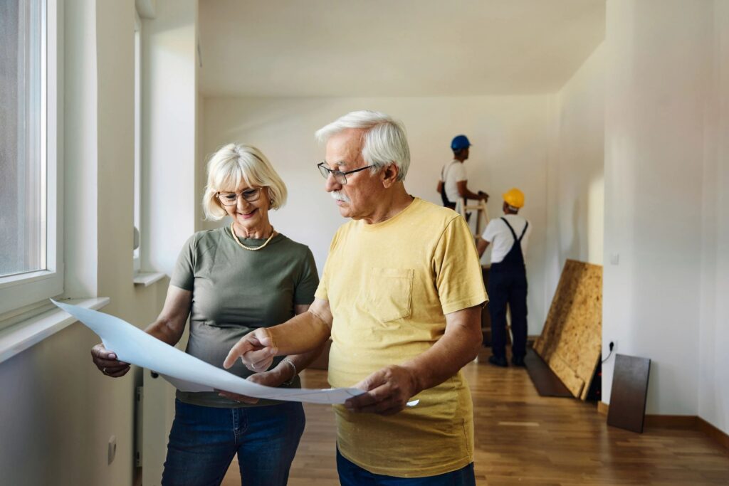 Happy mature couple reading blueprints during home renovation process.